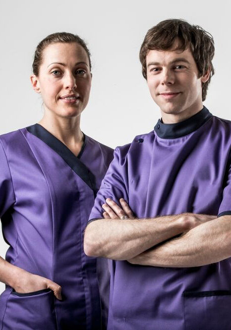 A man and woman in purple scrubs posing for the camera.